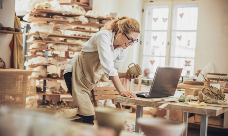 Potter entrepreneur using laptop  in workshop 
