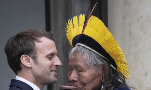 Brazil's legendary indigenous chief Raoni Metuktire (R) embraces French President Emmanuel Macron (L) after their meeting at the Elysee Palace on May 16, 2019 in Paris, part of the Brazilian leader's three-week tour across Europe where they will meet heads of state, celebrities and the Pope to highlight growing threats to the Amazon. - The elderly Kayapo chief, internationally recognisable through his traditional lip plate and feather headdress, will seek to raise one million euros (1,1 million USD) to better protect the Amazon's Xingu reserve, home to many of Brazil's tribal peoples, from loggers, farmers and fire. (Photo by Thomas SAMSON / AFP) (Foto: Thomas SAMSON / AFP)