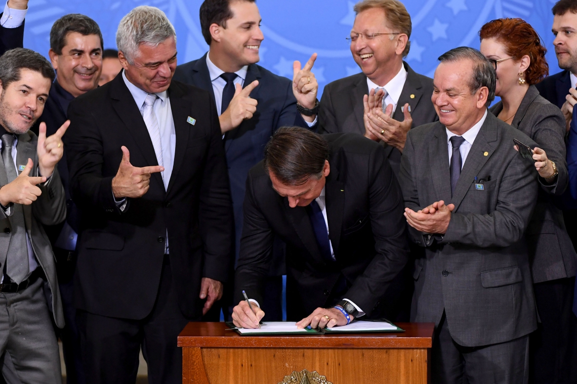 Bolsonaro assina o decreto das armas, para alegria de aliados e aliadas (Foto: EVARISTO SA / AFP)