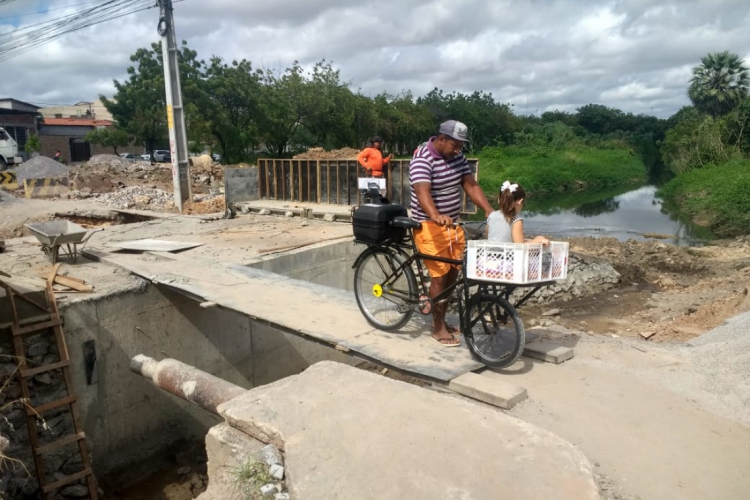José Maria Oliveira e sua filha atravessam a ponte na Rua Holanda, na Maraponga.(foto: Leonardo Maia/Especial para O POVO)