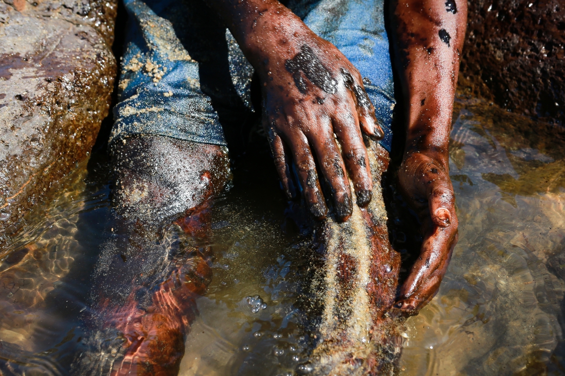 NA PRAIA DE Itapuama, Pernambuco, menino limpa o corpo coberto de óleo  (Foto:  LEO MALAFAIA / AFP)