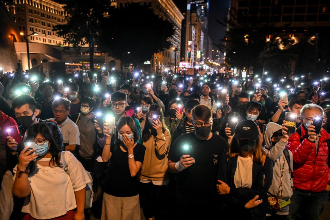 Manifestantes seguram seus celulares em Hong Kong: no Brasil, monitoramento oferecido pelas operadoras ajuda a mensurar isolamento social (Foto: YE AUNG THU / AFP)