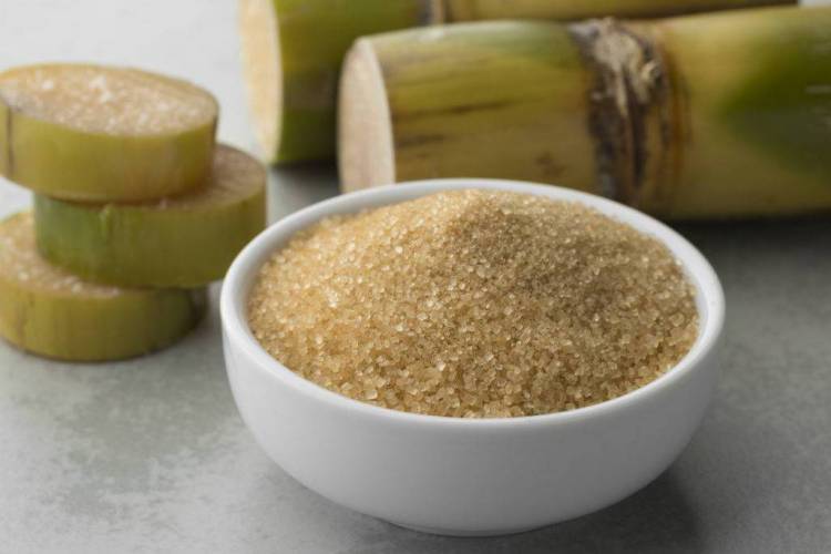 Tigela com açúcar e pedaço de cana ao fundo 