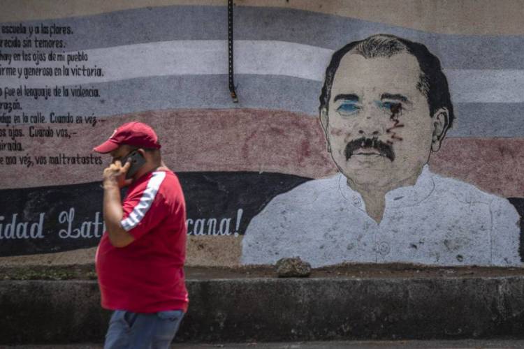 Um homem passa em frente a mural vandalizado de Daniel Ortega, presidente da Nicarágua