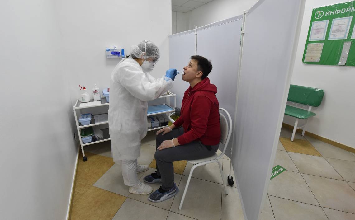 Equipe médica tira uma amostra de saliva de um homem em uma instalação de testes de Covid-19 em Moscou  (Foto: Vasily MAXIMOV / AFP)