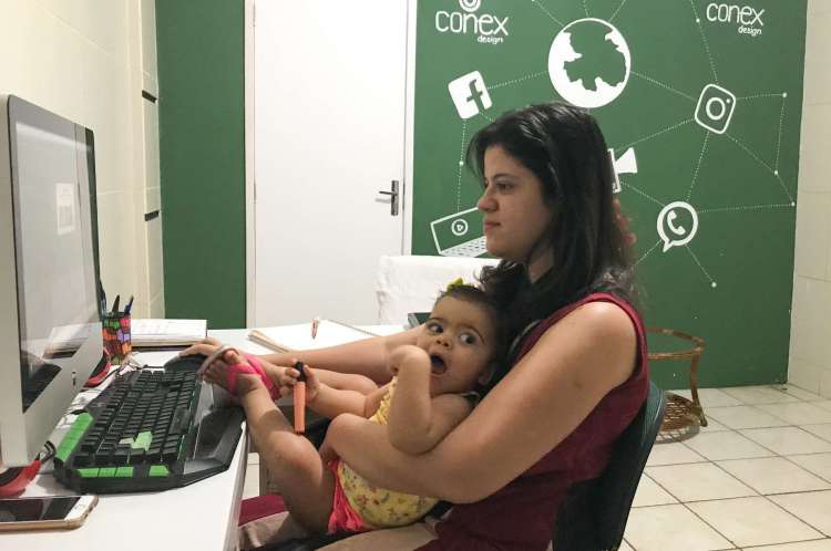 Karina Gomes, trabalhando de home office e, ao mesmo tempo, precisando dar atenção à filha