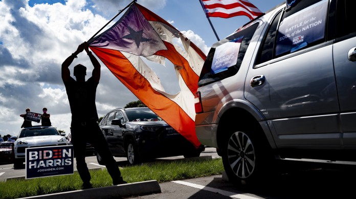 Apoiador do democrata Joe Biden segura a bandeira de Porto Rico próxima à bandeira dos Estados Unidos