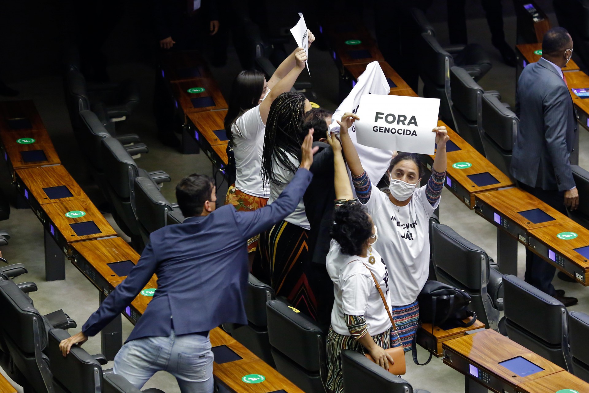 Opositores do governo do presidente Jair Bolsonaro se manifestam com cartazes e camisetas com os dizeres â.GenocÃ­dio foraâ.. durante discurso na sessÃ£o do Congresso Nacional em BrasÃ­lia, em 3 de fevereiro de 2021. - O Congresso brasileiro elegeu na segunda-feira dois aliados do presidente Jair Bolsonaro Ã  frente do Senado e da CÃ¢mara, uma importante vitÃ³ria do lÃ­der da extrema direita em sua busca por revigorar seus esforÃ§os de reeleiÃ§Ã£o para 2022. (Foto Sergio Lima / AFP) (Foto: Sergio Lima / AFP)
