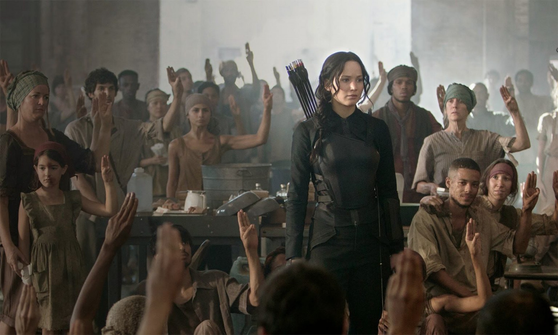Personagens de "Jogos Vorazes: A Esperança – Parte 1" fazendo o gesto, símbolo da rebelião liderada por Katniss Everdeen