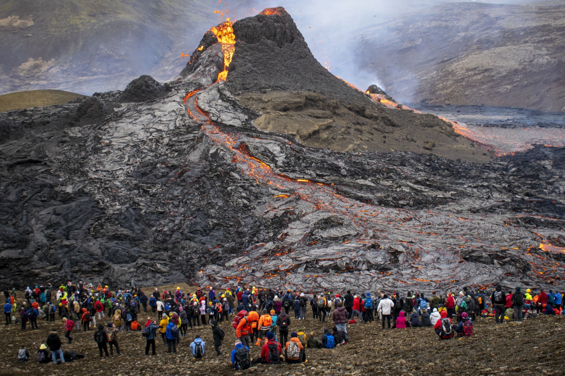 Os caminhantes de domingo observam a lava fluindo do vulcão em erupção Fagradalsfjall cerca de 40 km a oeste da capital da Islândia (Foto: Jeremie RICHARD / AFP)