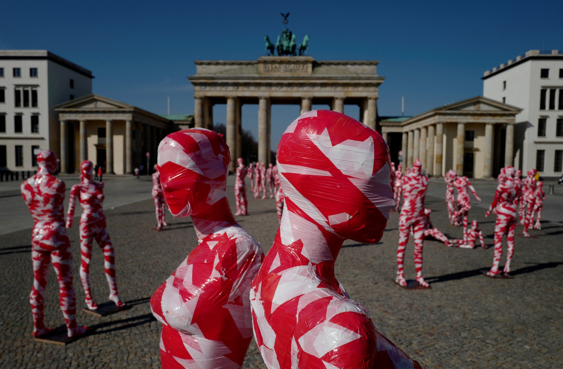 Manequins enrolados em fita isolante ficam em frente ao famoso Portão de Brandemburgo em Berlim em 31 de março de 2021, como parte do Corona Memorial do artista alemão Dennis Josef Meseg chamado 