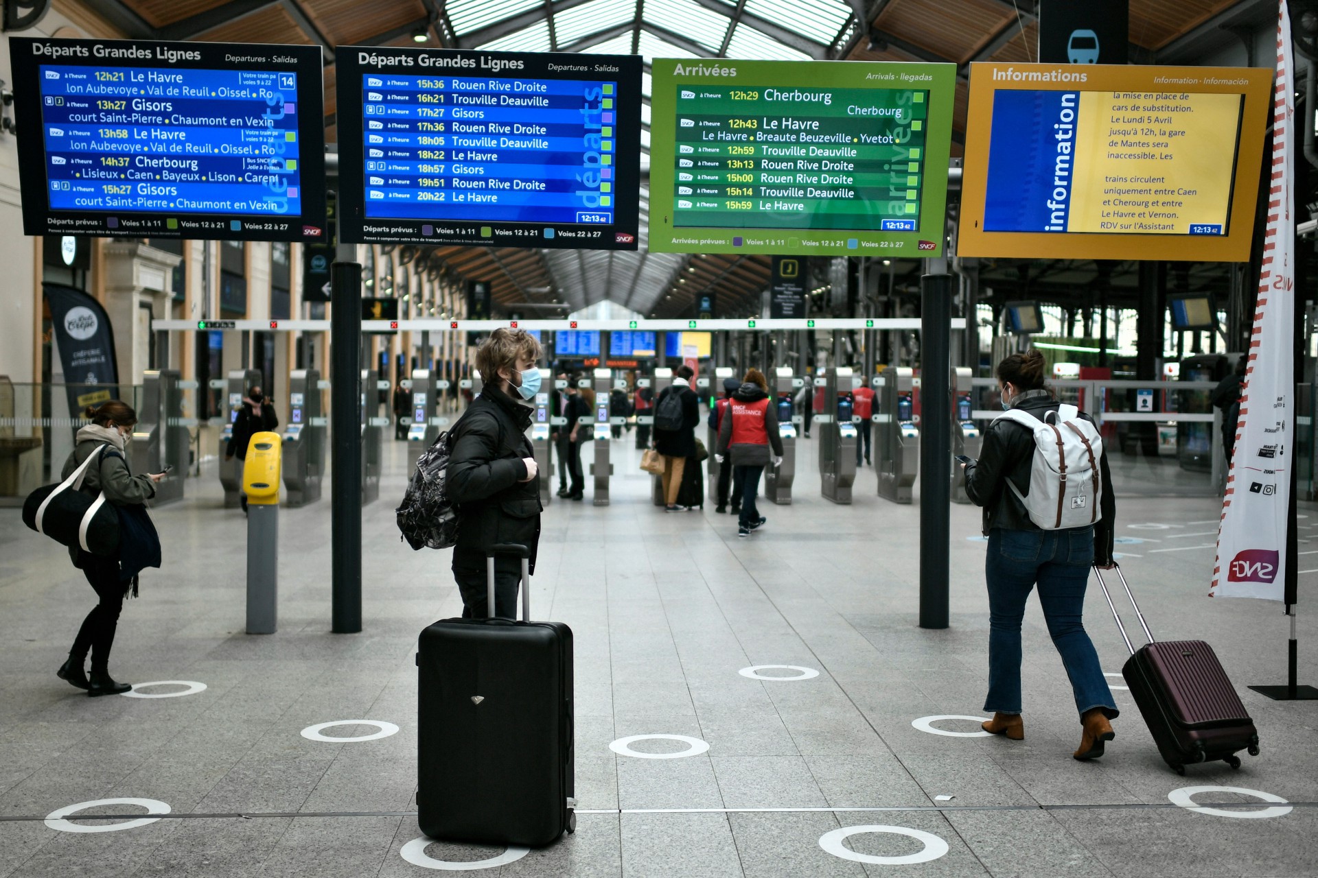Alguns poucos passageiros esperam, com suas bagagens, na estação de Saint-Lazare em Paris 