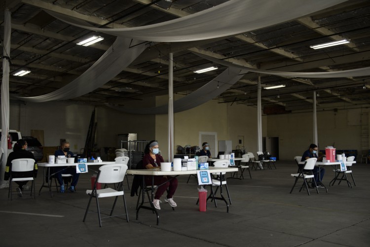 Enfermeiras esperam em mesas vazias até que mais pacientes cheguem para receber uma dose da vacina Moderna Covid-19 no local de vacinação do Sistema de Saúde de Long Beach, California