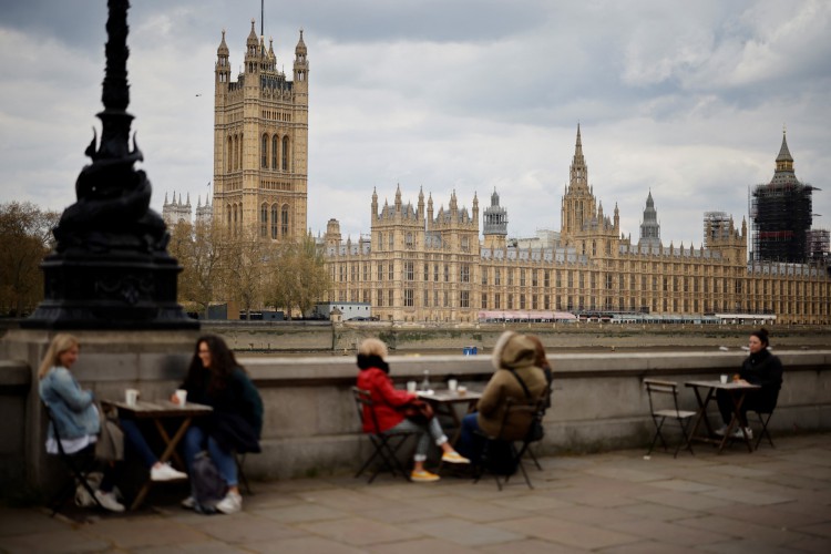 O público se senta em mesas ao longo do dique em frente às Casas do Parlamento no centro de Londres em 30 de abril de 2021