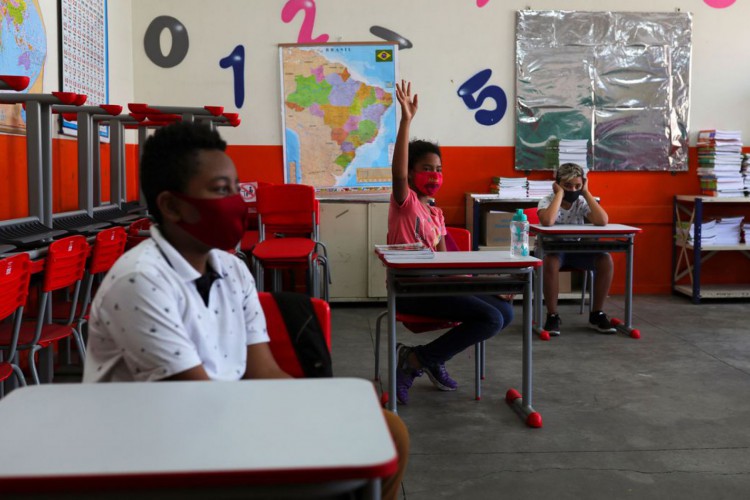 Criança levanta a mão ao lado de outros alunos em sala de aula da escola Thomaz Rodrigues Alckmin, no primeiro dia de retorno das escolas do estado de São Paulo para atividades extracurriculares em meio ao surto de coronavírus (COVID-19) em São Paulo, Brasil Outubro 7, 2020. REUTERS / Amanda Perobelli