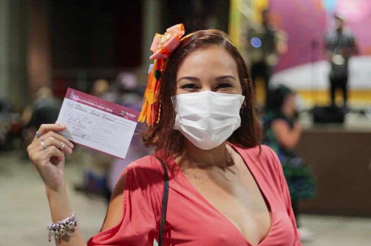 Ilana Brasil exibe cartão de vacinação após ser imunizada no "Arraiá de Vacinação" no Centro de Eventos