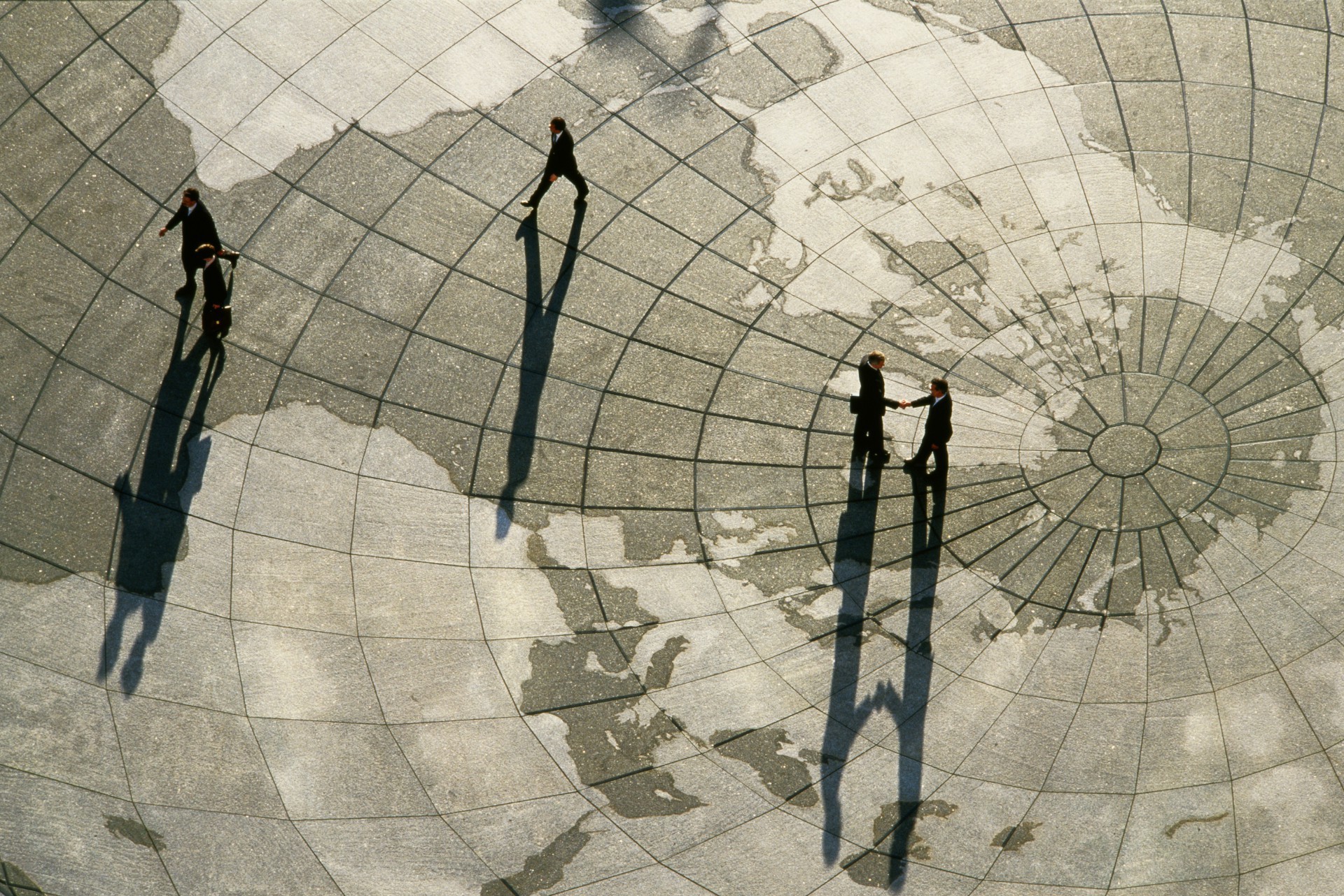Foto de stock de Businessmen on world map, two shaking hands, elevated view. Comércio internacional (Foto: Greg Pease/GettyImages)