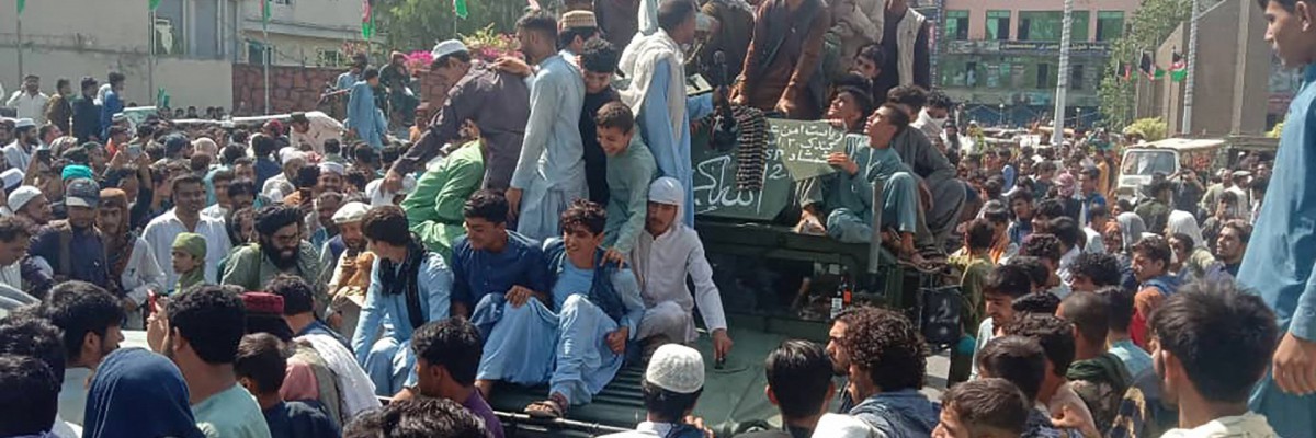 Combatentes do Taleban e moradores locais sentam-se em um veículo humvee do Exército Nacional Afegão (ANA) em uma rua da província de Jalalabad em 15 de agosto de 2021