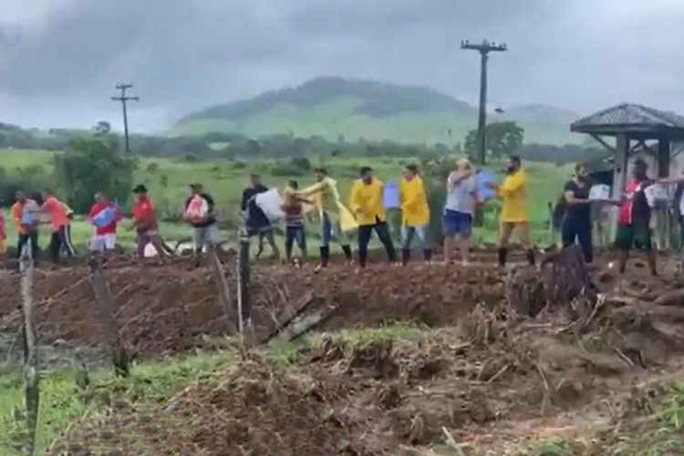 Caminhão com doações tem viagem interrompida por cratera e moradores fazem corrente para levar doações 