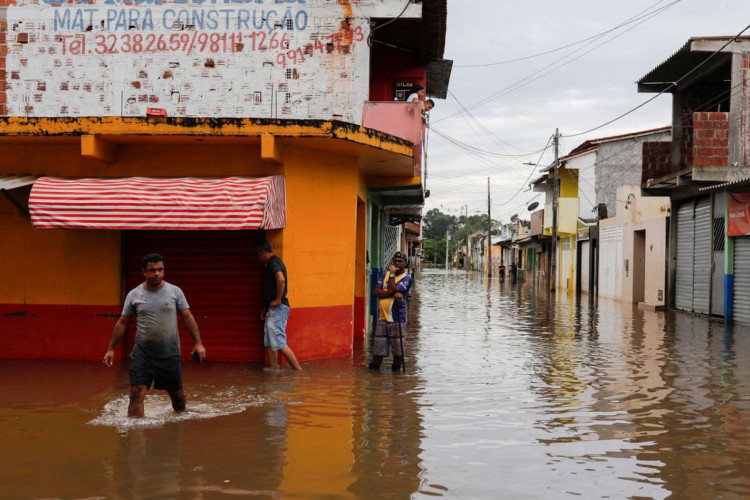 People walk through water along a street during floods caused by heavy rain in Itajuipe, Bahia state, Brazil December 27, 2021. REUTERS/Amanda Perobelli