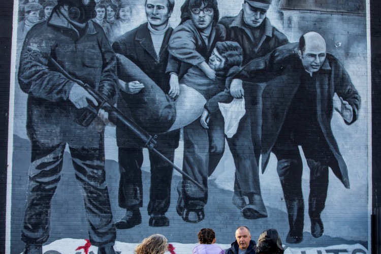 Pessoas diante de mural em memória do 