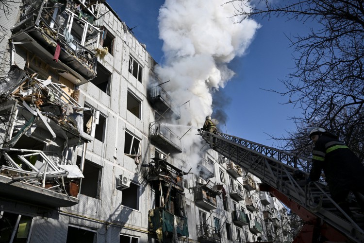 Bombeiros trabalham em um incêndio em um prédio após bombardeios na cidade de Chuguiv, no leste da Ucrânia, em 24 de fevereiro de 2022, enquanto as forças armadas russas tentam invadir a Ucrânia em várias direções.