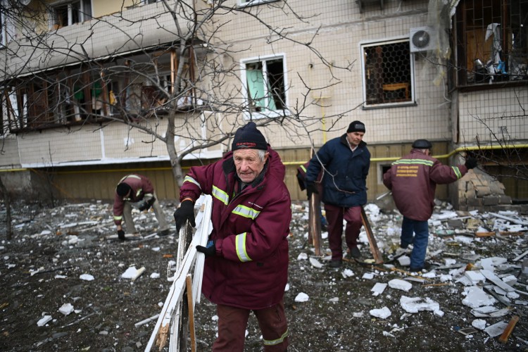 Homens limpam destroços em um prédio residencial danificado na rua Koshytsa, um subúrbio da capital ucraniana Kiev, onde um bombardeio militar supostamente atingiu, em 25 de fevereiro de 2022