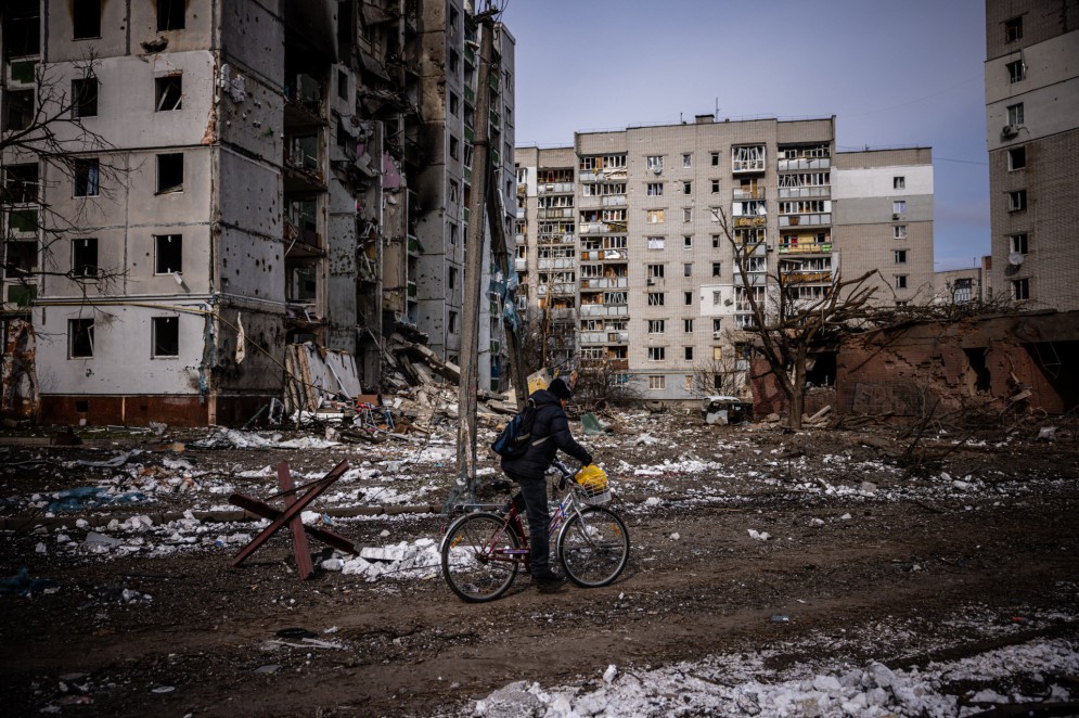 Homem passa de bicicleta próximo a prédios residenciais destruídos na cidade ucraniana de Chernihiv, durante ataques da Rússia em 2022(Foto: Dimitar Dilkoff / AFP)