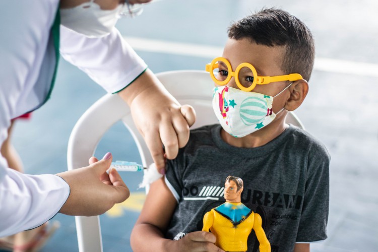 Pedro Miguel, 7 anos, levou um boneco de super-herói para dar "coragem e força" na hora de tomar a vacina.