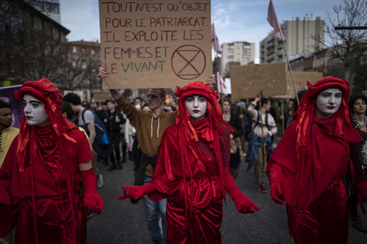 As mulheres seguram um cartaz que diz: "Tudo é um objeto para o patriarcado. Ele explora as mulheres e os vivos" durante uma manifestação para pedir mais direitos para as mulheres, como parte do Dia Internacional da Mulher em Toulouse, sudoeste da França, em março 8 de 2022. 