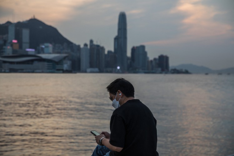 Um homem usa seu telefone em um calçadão ao lado do Victoria Harbour, em Hong Kong, em 15 de março de 2022