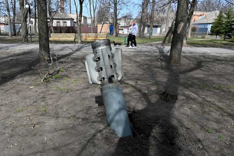 Ucranianos caminham atrás de um fragmento de foguete nos arredores de Chuguiv, região de Kharkiv, em 8 de abril de 2022