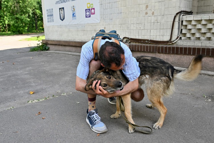 Yuriy Manko, um voluntário de 31 anos, abraça um cachorro do lado de fora de um abrigo temporário de animais na capital ucraniana, Kyiv, em 9 de junho de 2022