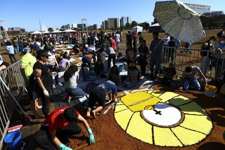Fiéis confeccionam os tradicionais tapetes de serragem durante a Festa de Corpus Christi de Brasília, que retorna à Esplanada dos Ministérios após 2 anos de celebrações reduzidas por conta da pandemia.