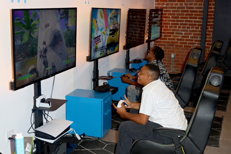 Nesta foto de arquivo tirada em 10 de agosto de 2022, os convidados jogam videogames durante a inauguração do SoLa Tech and Entrepreneurship Center Powered by Riot Games em Los Angeles, Califórnia. No auge da pandemia, os videogames ofereciam consolo às pessoas isoladas. Mas agora que a vida está voltando lentamente ao normal pré-crise e a inflação está subindo, as empresas de jogos estão sentindo o aperto