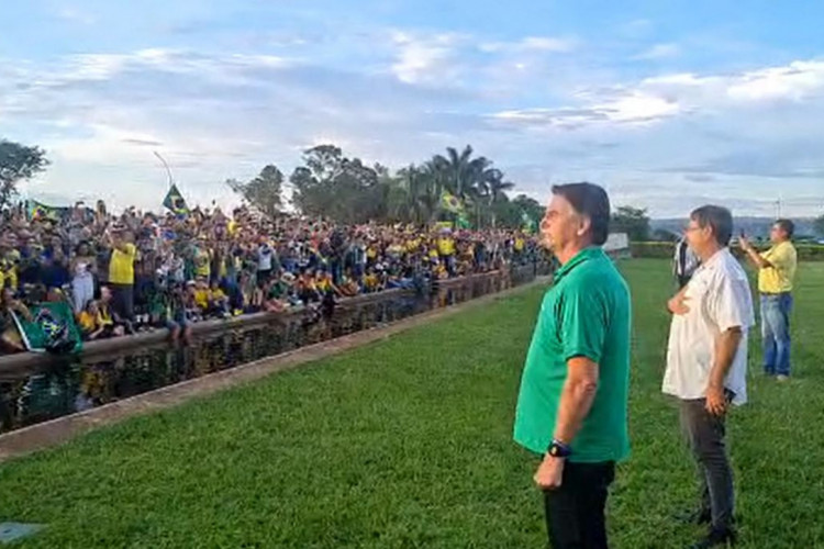 Bolsonaro observa apoiadores, neste domingo, mas ap&oacute;s longo sil&ecirc;ncio sua &uacute;nica frase dita foi "boa noite a todos voc&ecirc;s"
