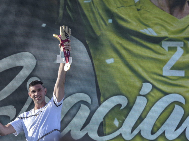 O goleiro da seleção argentina Emiliano Martinez segura medalha de ouro e troféu luva de ouro concedidos pela FIFA durante homenagem a ele, em Mar del Plata, Argentina, em 22 de dezembro de 2022, ao retornar à sua cidade natal após vencer o Catar 2022 torneio da Copa do Mundo 