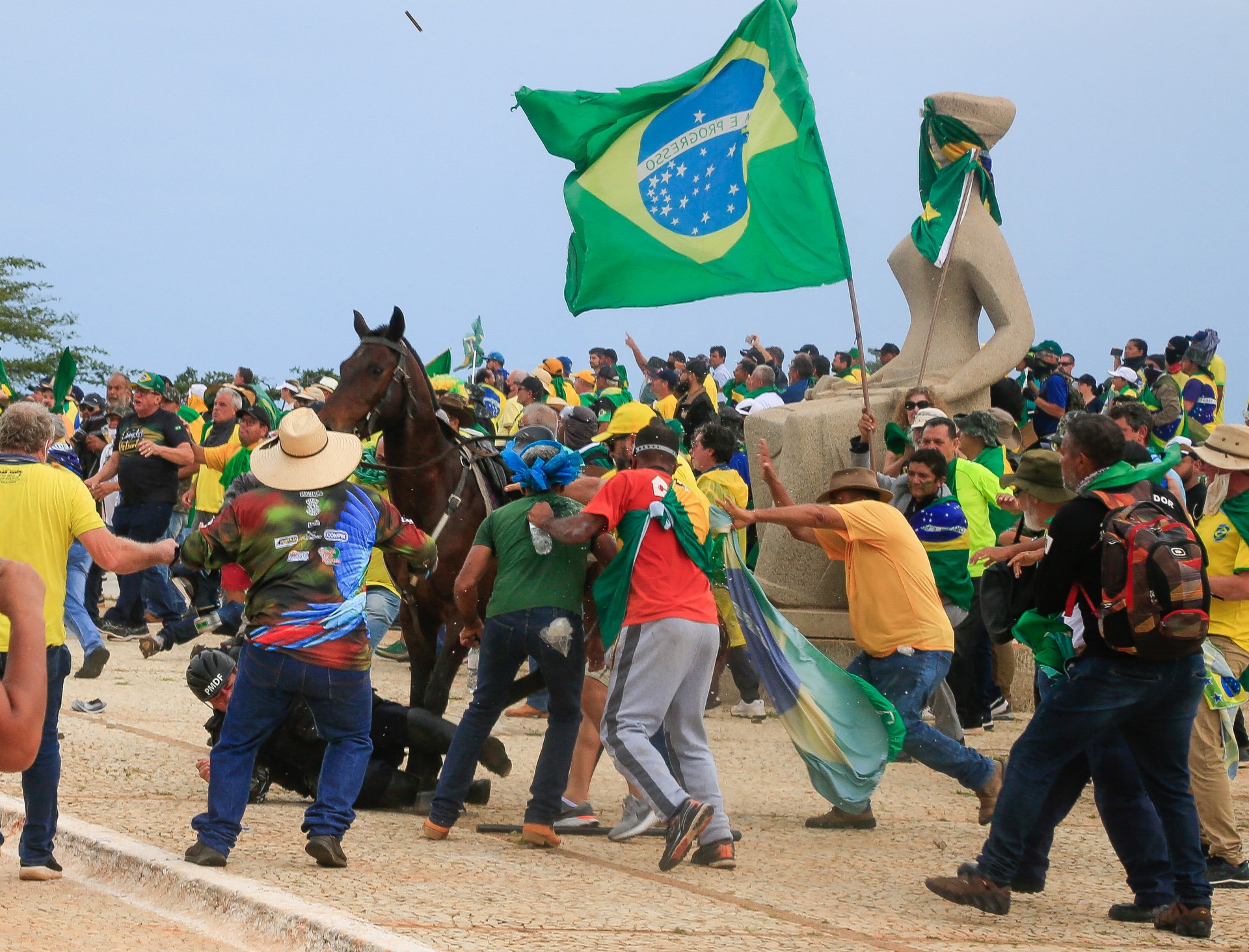 Um policial militar cai de seu cavalo durante confrontos com apoiadores do ex-presidente brasileiro Jair Bolsonaro, em frente ao STF (Foto: SERGIO LIMA/AFP)