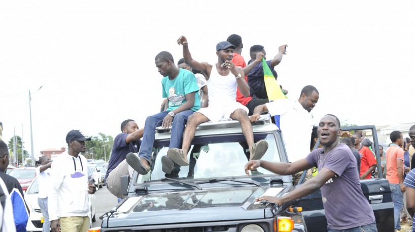 Pessoas gesticulam e seguram bandeira nacional do Gabão enquanto comemoram em Libreville em 30 de agosto de 2023, depois que militares apareceu na televisão anunciando que estavam 