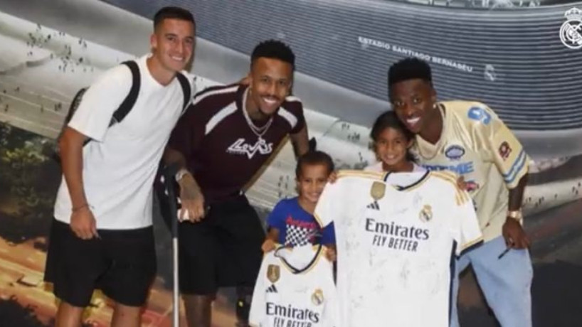 Lucas Vázquez, Éder Militão e Vinicius Junior, do Real Madrid, ao lado da criança que sofreu racismo por parte da torcida do Atlético de Madrid.