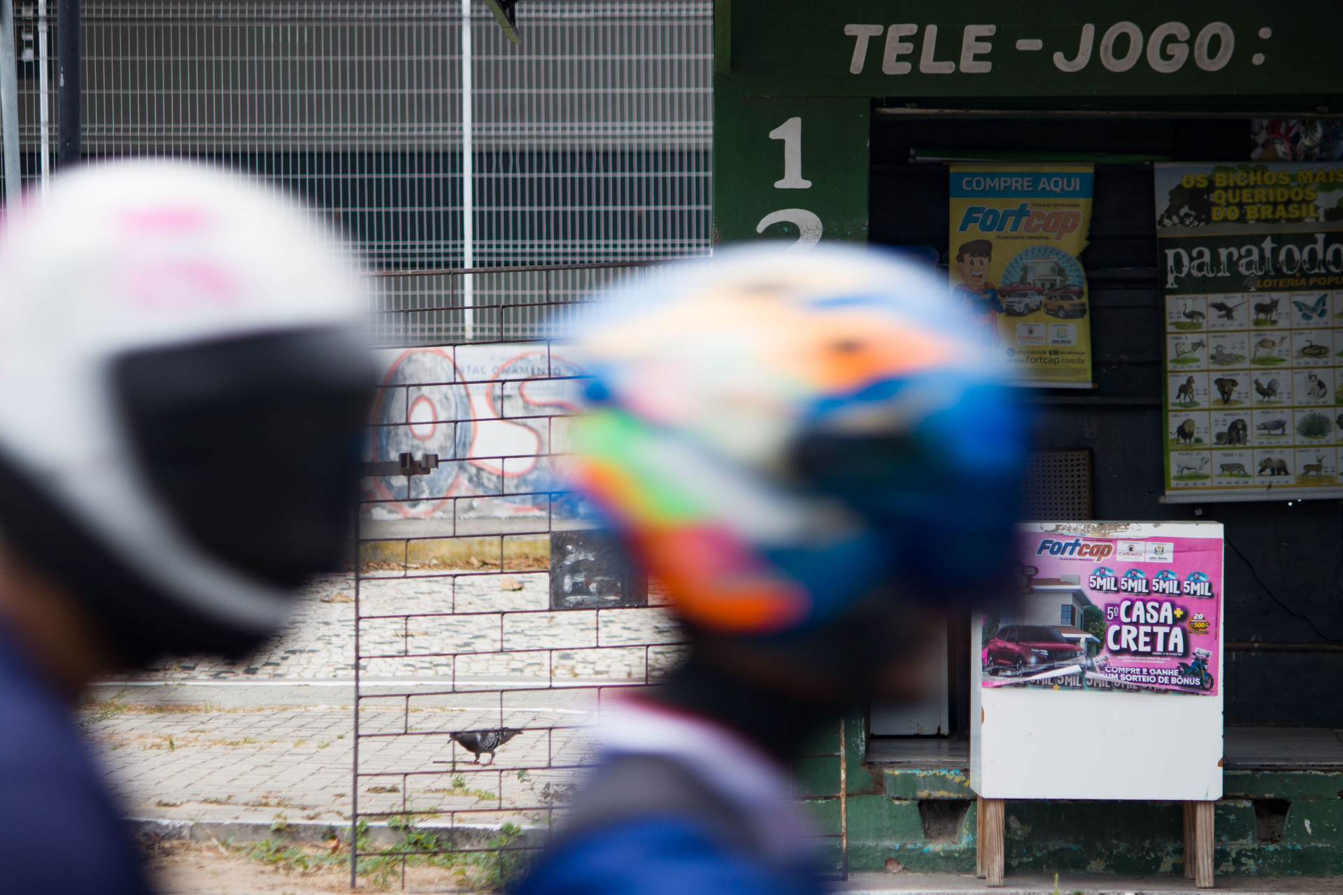 ￼Homens de moto passam em frente a uma casa de apostas (Foto: Fotos: Samuel Setubal)