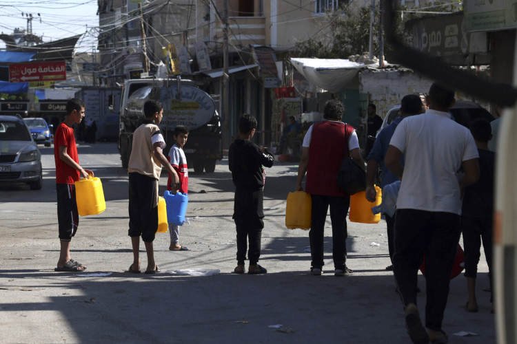 Palestinos fazem fila por água no campo de refugiados de Rafah, no sul da Faixa de Gaza, em 15 de outubro de 2023. Comboios de ajuda humanitária empilhados perto da fronteira do Egito com a Faixa de Gaza no domingo, incapazes de entrar no enclave palestino que está sendo bombardeado por Israel, testemunhas disseram à AFP
