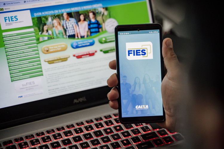 FORTALEZA-CE, BRASIL, 04-11-2023: Foto mostra celular com o app do Fies em frente a um notebook com o endereço eletrônico do FIES. (Foto: Júlio Caesar/O Povo) 