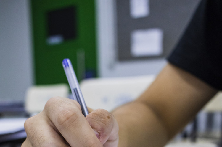 Close em m&atilde;os escrevendo em livro 