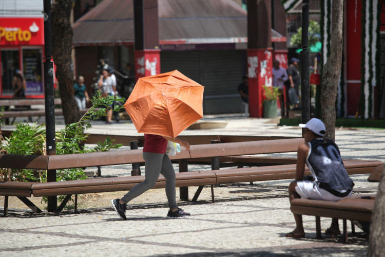 A previsão de tempo para esta segunda-feira, 27, é de sol e poucas nuvens. Na foto, pedestre usa sombrinha como proteção contra luz solar, no Centro de Fortaleza