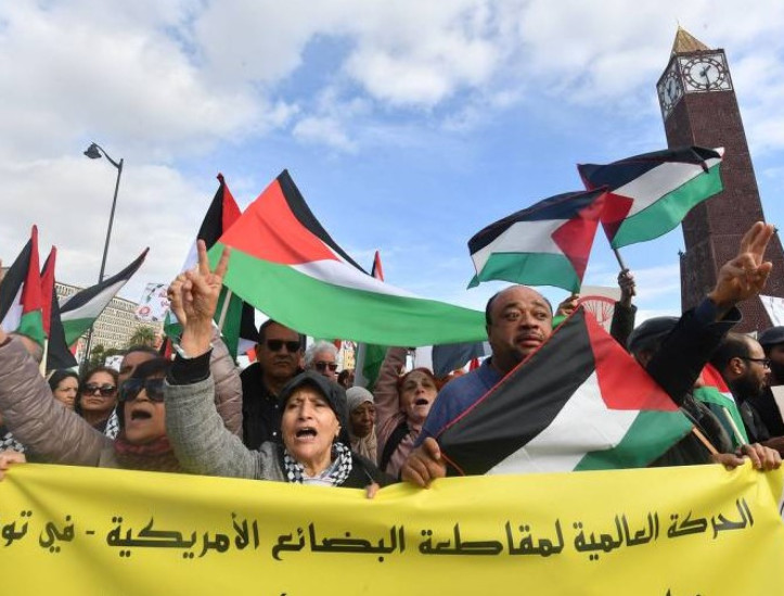  Na Tunísia, manifestantes exibem bandeiras da Palestina e faixa em árabe que pede um boicote aos Estados Unidos pelo apoio a Israel na guerra contra o Hamas em Túnis 
