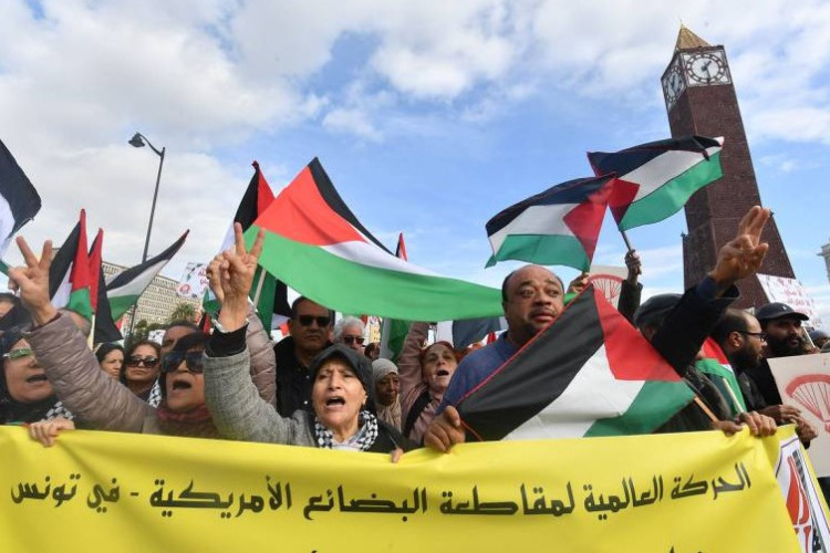  Na Tunísia, manifestantes exibem bandeiras da Palestina e faixa em árabe que pede um boicote aos Estados Unidos pelo apoio a Israel na guerra contra o Hamas em Túnis