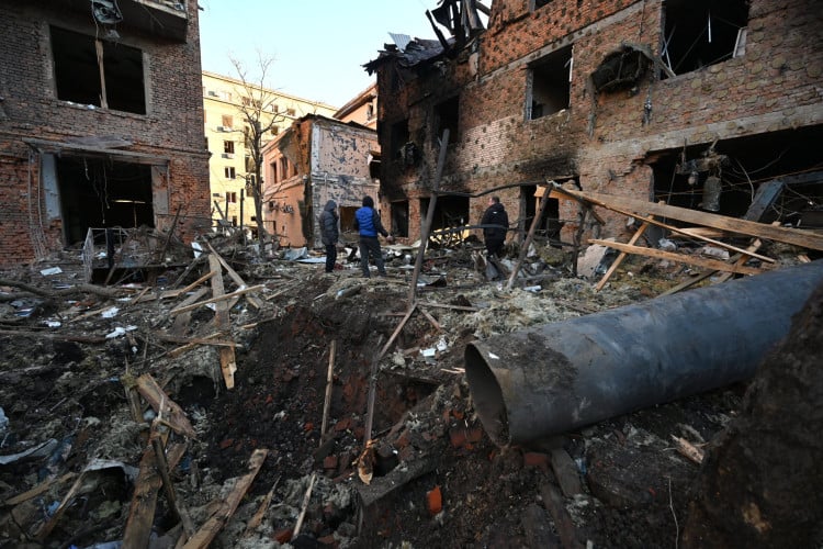 Moradores inspecionam em um prédio residencial após o ataque de drones russos na cidade de Kharkiv (ou Carcóvia), em 31 de dezembro de 2023, em meio à invasão russa da Ucrânia 