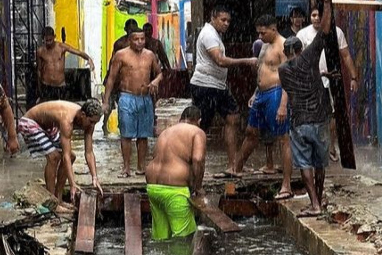 Moradores tentam desobstruir canal localizado no Beco do Céu, no bairro Vila Velha, após chuva deixar local alagado