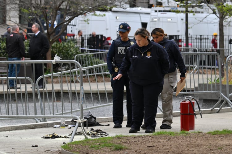 Policiais investigam a cena depois que um homem ateou fogo a si mesmo no parque em frente ao Tribunal durante o julgamento de Donald Trump